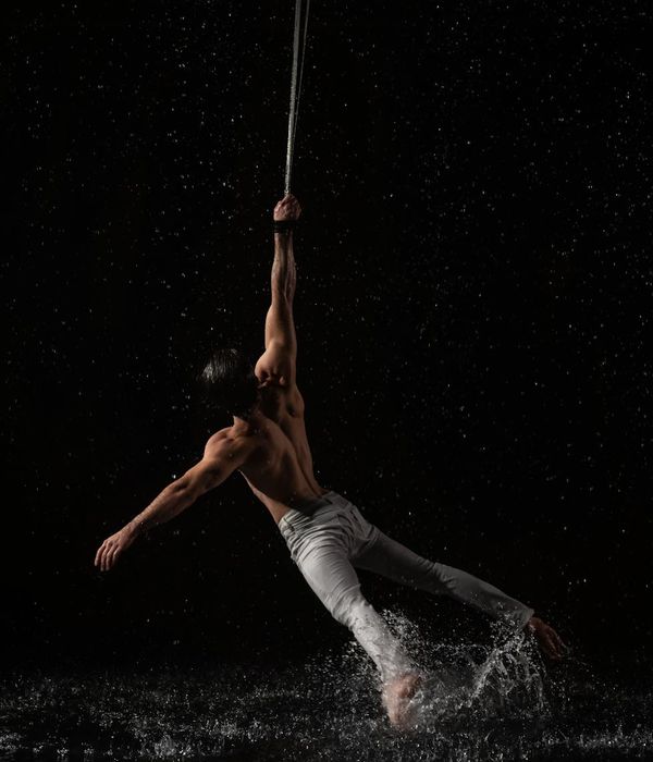 Man performing a controlled strength exercise in a dark studio.